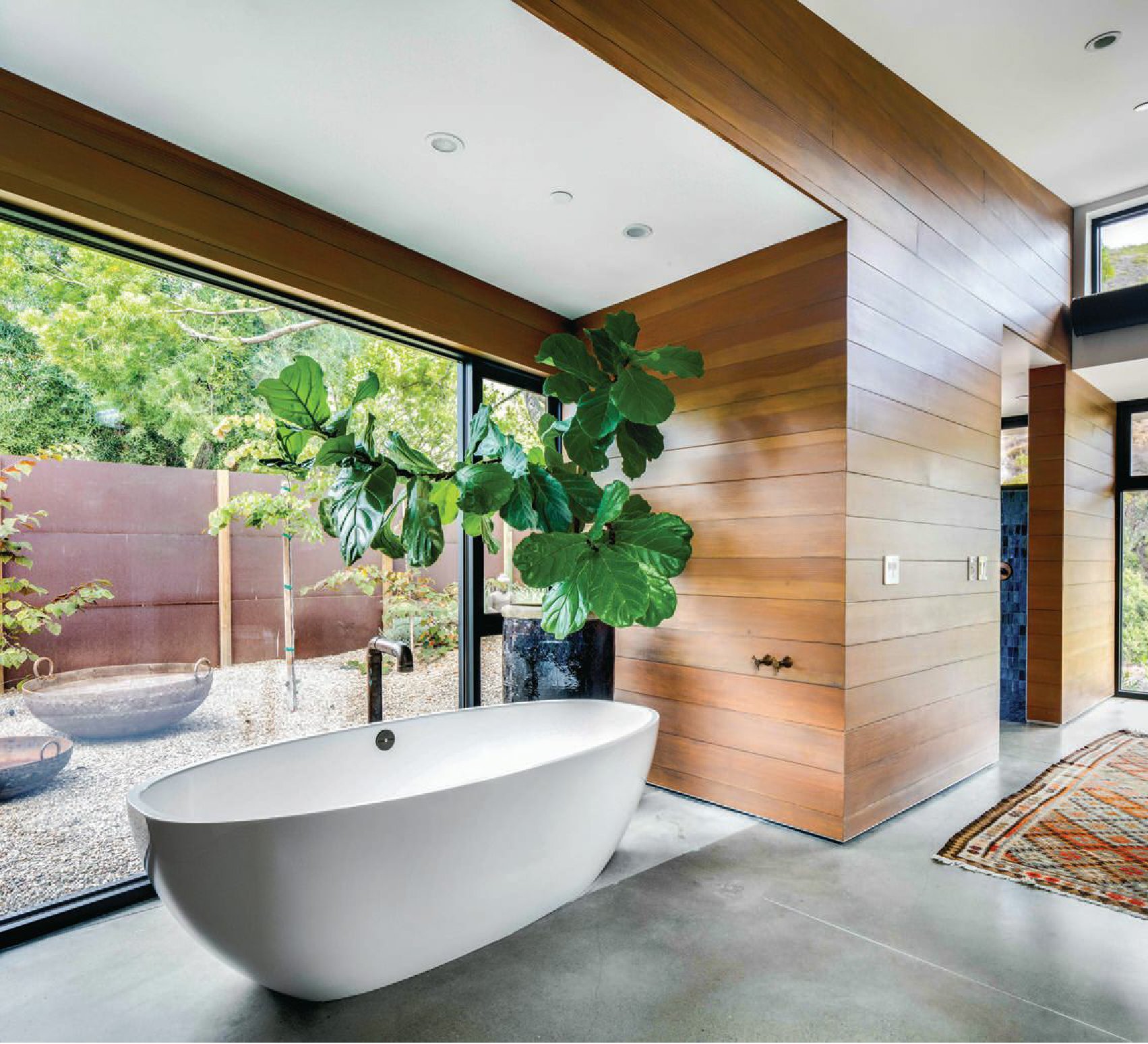 In the primary suite, Pirch’s Victoria    Albert free-standing soaker tub,  which sports a faucet designed by the  owner and constructed from plumbing  parts, overlooks a private yard  enclosed by a fence fabricated from  Corten steel. The rug was found at The  Garage Collective in Laguna Beach. PHOTOGRAPHED BY CHAD MELLON