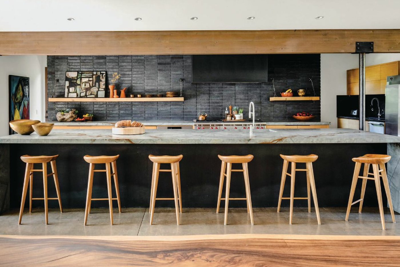 The kitchen is separated from  the dining area by a long island with a honed granite countertop. The stools were found at HD Buttercup. The  backsplash’s black brick was discovered at a building supply store. PHOTOGRAPHED BY CHAD MELLON